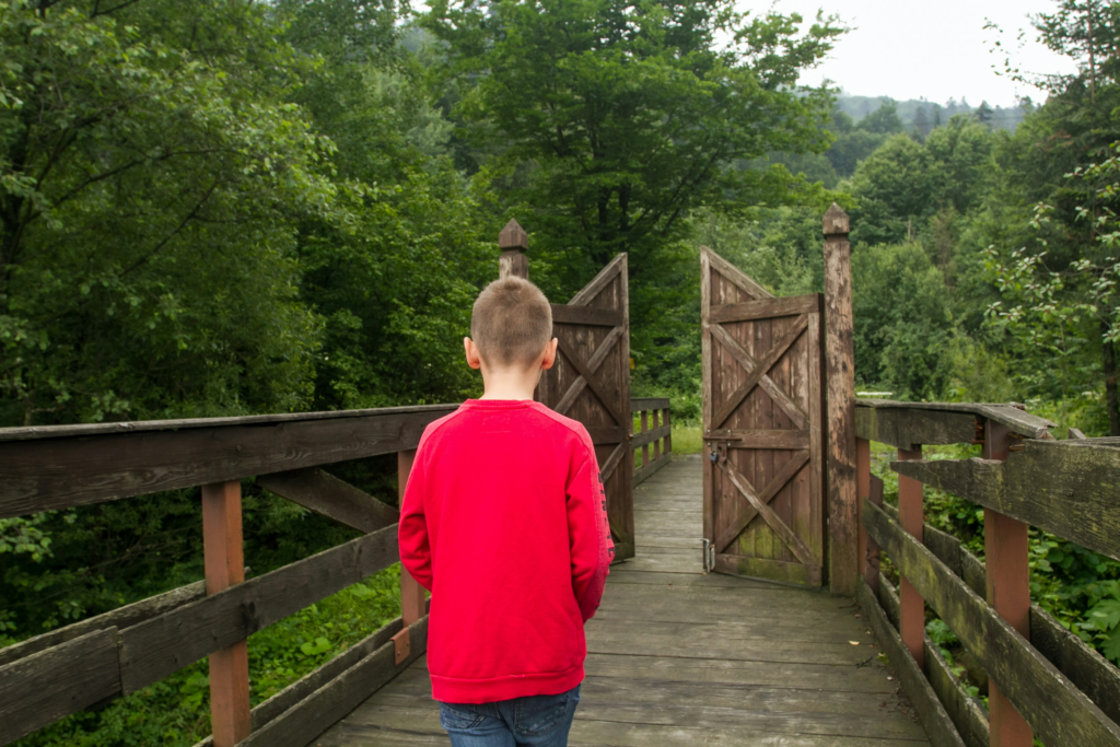 Boy in red top walkling towards a gate