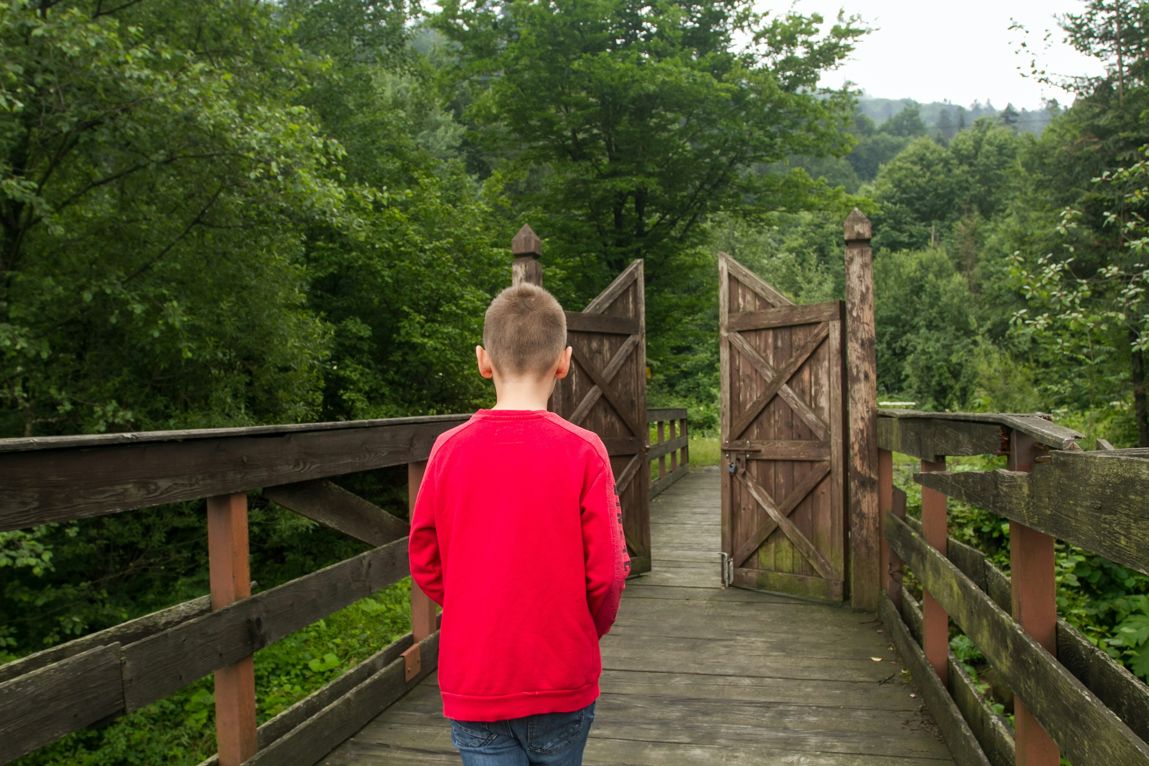Boy in red top walkling towards a gate