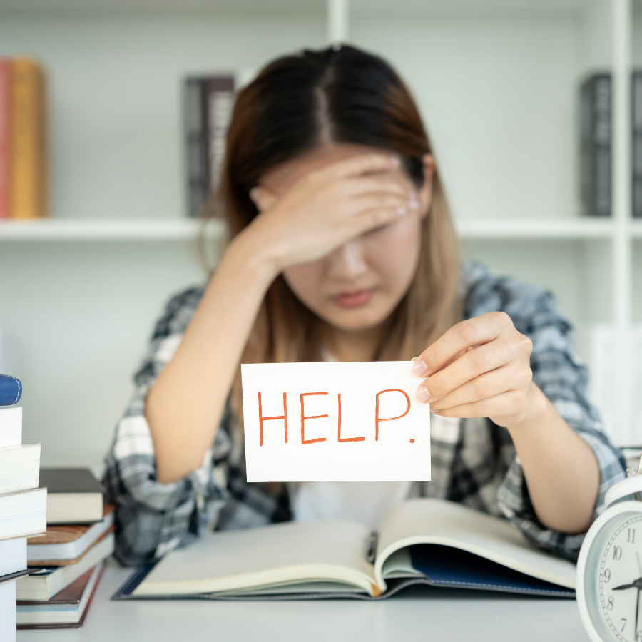 Person looking overwhelmed, holding up a sticky note saying "help"