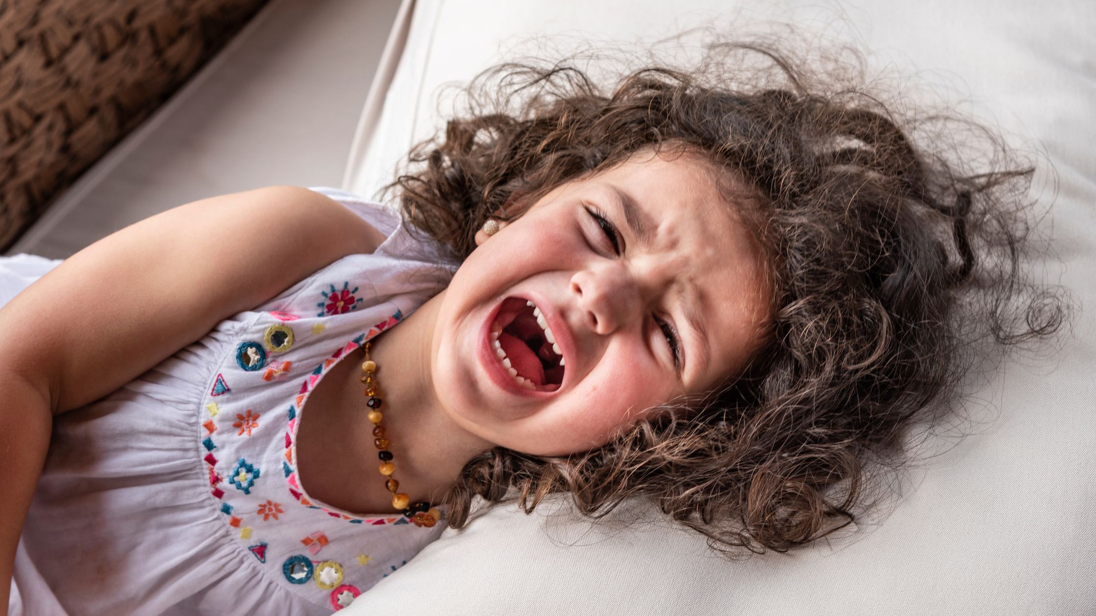 Child lying down, looking very unhappy and screaming
